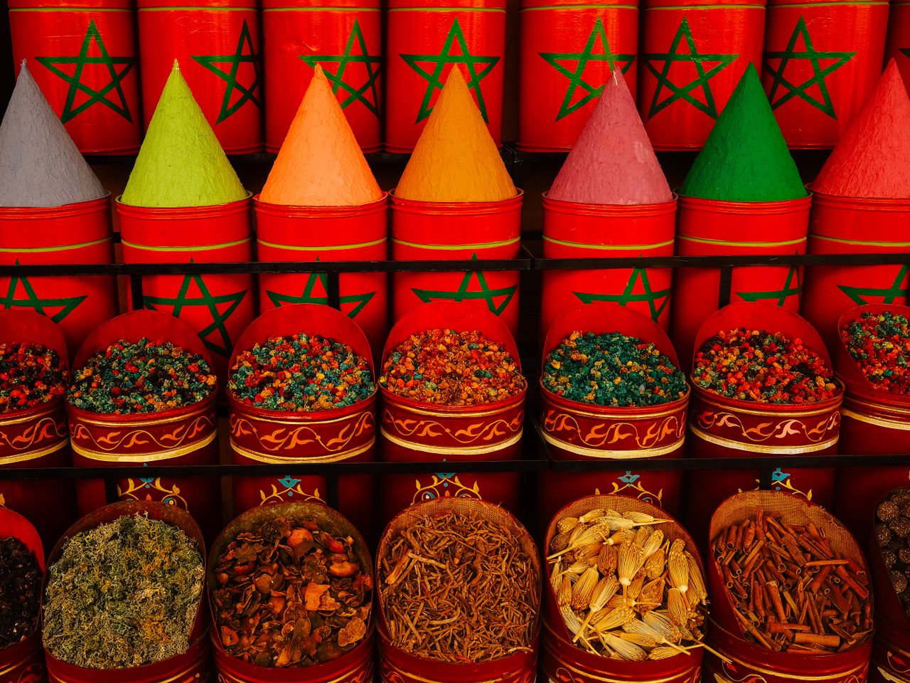 Vibrant display of traditional spices in Moroccan market with colorful cones and aromatic herbs.